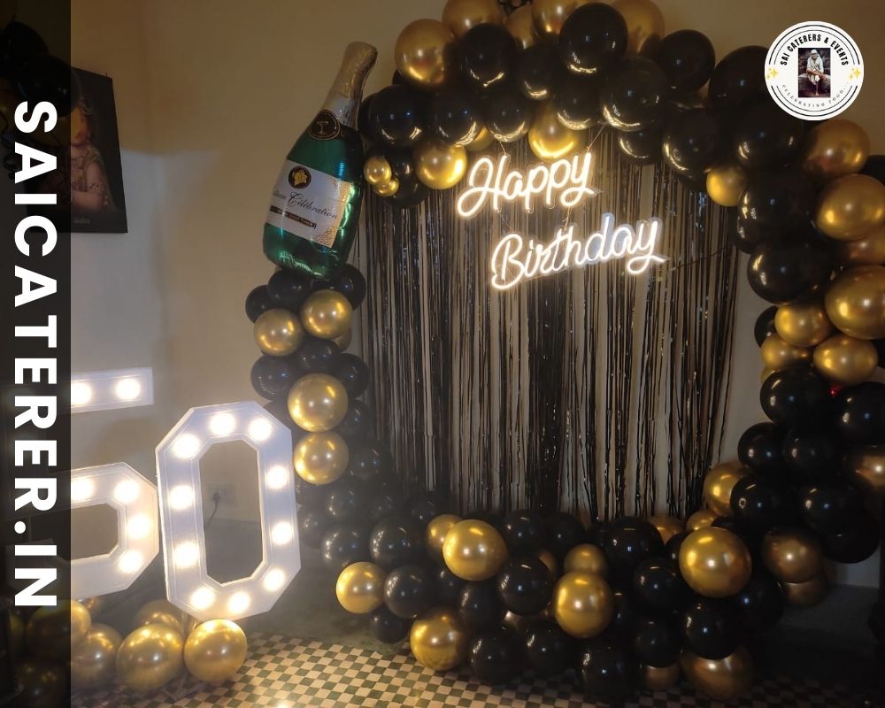 Birthday catering setup with black balloon decoration and neon yellow lights for 50th celebration